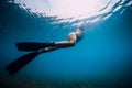 Sporty woman freediver with fins glides underwater in blue sea Royalty Free Stock Photo