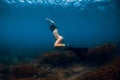 Sporty woman freediver with fins glides underwater in blue sea Royalty Free Stock Photo