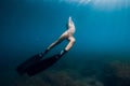 Sporty woman freediver with fins glides underwater in blue sea Royalty Free Stock Photo