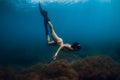 Sporty woman freediver with fins glides underwater in sea. Freediving in ocean Royalty Free Stock Photo