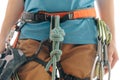 Sporty woman in harness with climbing and mountaineering equipment.