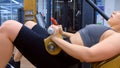 Sporty woman making exercise for booty on training machine, side view.