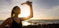 sporty woman pouring refreshing water on face from bottle after outdoor fitness workout on beach