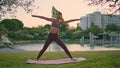 Sporty woman practicing asana raising up hand at sunset park. Yoga lady training Royalty Free Stock Photo