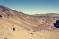 Sporty woman running down volcanic slope lifting dust trail.