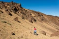 Sporty woman running down volcanic slope lifting dust trail.