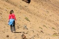 Sporty woman running down volcanic slope lifting dust trail.