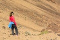 Sporty woman running down volcanic slope lifting dust trail.