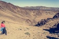 Sporty woman running down volcanic slope lifting dust trail.