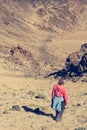 Sporty woman running down volcanic slope lifting dust trail.