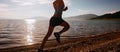 Sporty woman running on rocky seaside