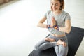 Sporty woman sitting cross-legged in lotus pose in bright room Royalty Free Stock Photo