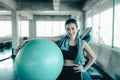 Sporty Woman in Sportswear is Resting Tired During Exercise While Holding Pilates Ball in Fitness Gym, Sport Asian Woman
