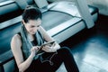 Sporty Woman in Sportswear is Sitting on Flooring While Using Tablet After Jogging Workout Break. Sport Asian Woman is Resting on