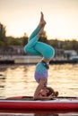 Sporty woman in yoga position on paddleboard, doing yoga on sup board, exercise for flexibility and stretching of Royalty Free Stock Photo