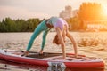 Sporty woman in yoga position on paddleboard, doing yoga on sup board, exercise for flexibility and stretching of Royalty Free Stock Photo