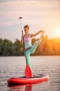 Sporty woman in yoga position on paddleboard, doing yoga on sup board, exercise for flexibility and stretching of Royalty Free Stock Photo