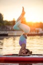 Sporty woman in yoga position on paddleboard, doing yoga on sup board, exercise for flexibility and stretching of Royalty Free Stock Photo