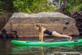 Sporty woman in yoga position on paddleboard, doing yoga on sup board, exercise for flexibility and stretching of Royalty Free Stock Photo