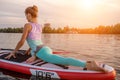 Sporty woman in yoga position on paddleboard, doing yoga on sup board, exercise for flexibility and stretching of Royalty Free Stock Photo