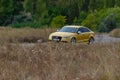 A sporty yellow sedan drives at high speed on an autumn paved ro Royalty Free Stock Photo