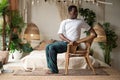 Sporty young african man practicing yoga using chair, doing Revolved Chair Pose, Parivrtta Utkatasana