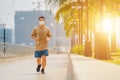 Sporty young asian man wearing face mask while jogging and running in park. Royalty Free Stock Photo