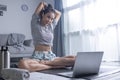 Sporty young Asian woman exercising at home, watching fitness video on Internet or having online fitness class Royalty Free Stock Photo