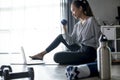 Sporty young Asian woman exercising at home, watching fitness video on Internet or having online fitness class Royalty Free Stock Photo