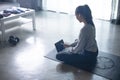 Sporty young Asian woman exercising at home, watching fitness video on Internet or having online fitness class Royalty Free Stock Photo