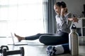 Sporty young Asian woman exercising at home, watching fitness video on Internet or having online fitness class, Royalty Free Stock Photo