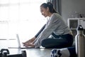 Sporty young Asian woman exercising at home, watching fitness video on Internet or having online fitness class Royalty Free Stock Photo