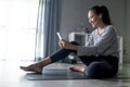 Sporty young Asian woman exercising at home, watching fitness video on Internet or having online fitness class Royalty Free Stock Photo