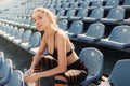 Sporty young attractive girl in sportswear relaxing after hard workout sit and drink water from bottle after running on a stadium Royalty Free Stock Photo