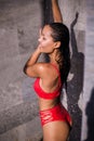 Sporty young beautiful woman in a red swimsuit taking refreshing shower after swimming in the outdoor pool. Outdoor