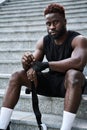 Sporty young black man sitting at urban stairs wrapping hands with boxing tape. Royalty Free Stock Photo