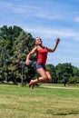 Sporty young blond woman jumping for happiness outdoors