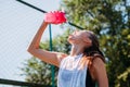 Sporty young blonde woman with sporty bottle with cool water pours water on herself on sports field Royalty Free Stock Photo