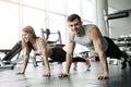 Sporty young couple doing plank exercise in gym