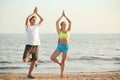 Sporty young couple practicing yoga on sea beach Royalty Free Stock Photo