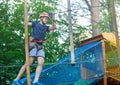 Sporty, young, cute boy in white t shirt spends his time in adventure rope park in helmet and safe equipment in the park Royalty Free Stock Photo