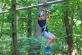 Sporty, young, cute boy in white t shirt spends his time in adventure rope park in helmet and safe equipment in the park Royalty Free Stock Photo