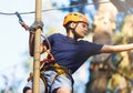 Sporty, young, cute boy in white t shirt spends his time in adventure rope park in helmet and safe equipment in the park Royalty Free Stock Photo