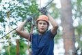 Sporty, young, cute boy in white t shirt spends his time in adventure rope park in helmet and safe equipment in the park Royalty Free Stock Photo