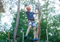 Sporty, young, cute boy in white t shirt spends his time in adventure rope park in helmet and safe equipment in the park Royalty Free Stock Photo