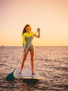 Sporty young girl stand up paddle surfing with beautiful sunset or sunrise colors Royalty Free Stock Photo