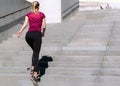 Sporty young girl in a top and leggings jogging ot the stairs. Pretty woman sporting. Concept of sport and health