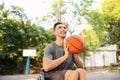 Sporty young man with ball sitting in wheelchair outdoors Royalty Free Stock Photo