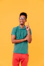 Sporty young man in glasses posing in studio. Gorgeous male model in green t-shirt smiling on yello Royalty Free Stock Photo