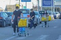 Sporty young man pushes full shopping cart in parking lot.Guy wears surgical face mask for corona virus infection,contagion contro